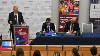 3 people talking in front of an audience in a conference hall.